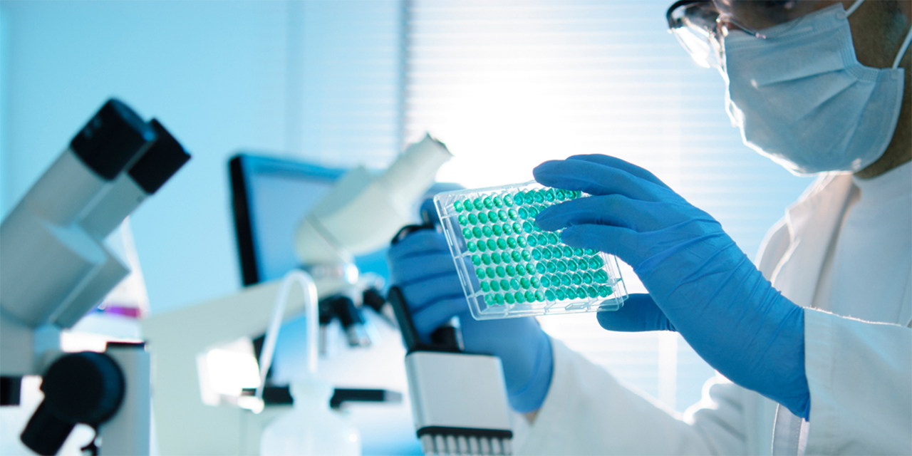 Person handling equipment in a lab with microscopes.