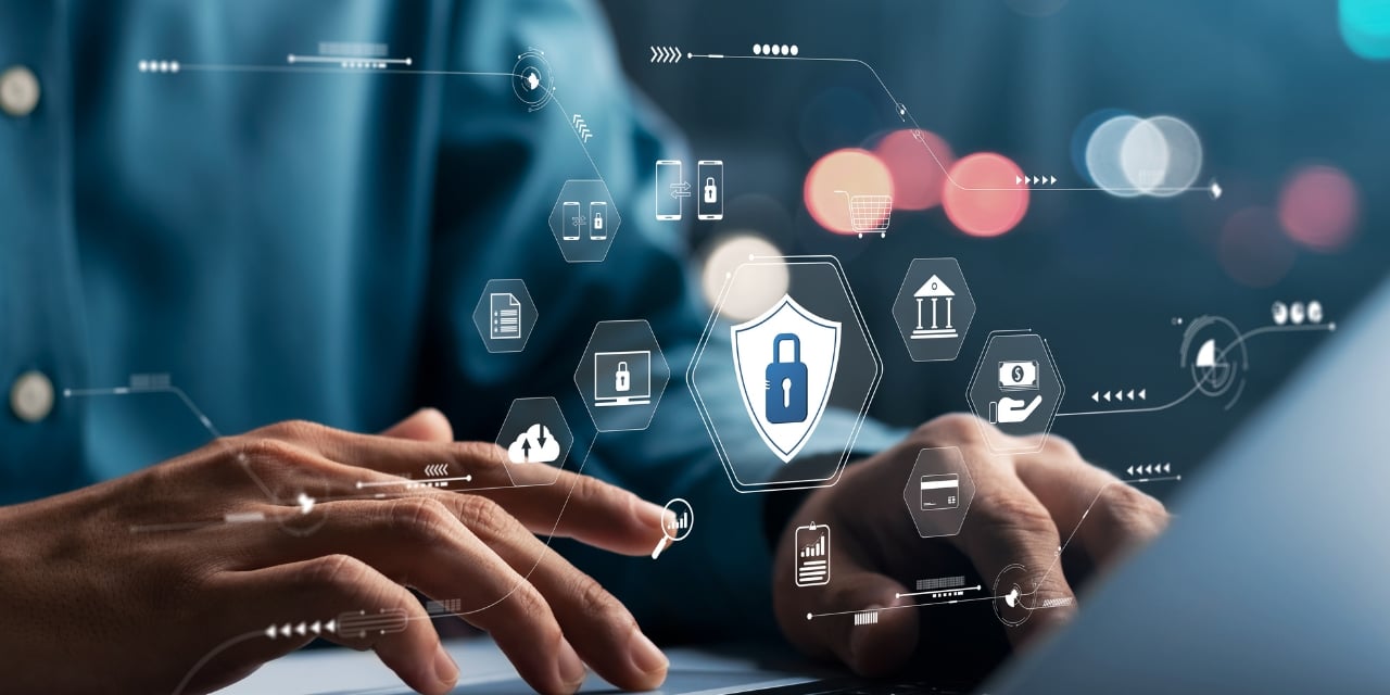 Hands typing on laptop with digital icons floating over top of image.