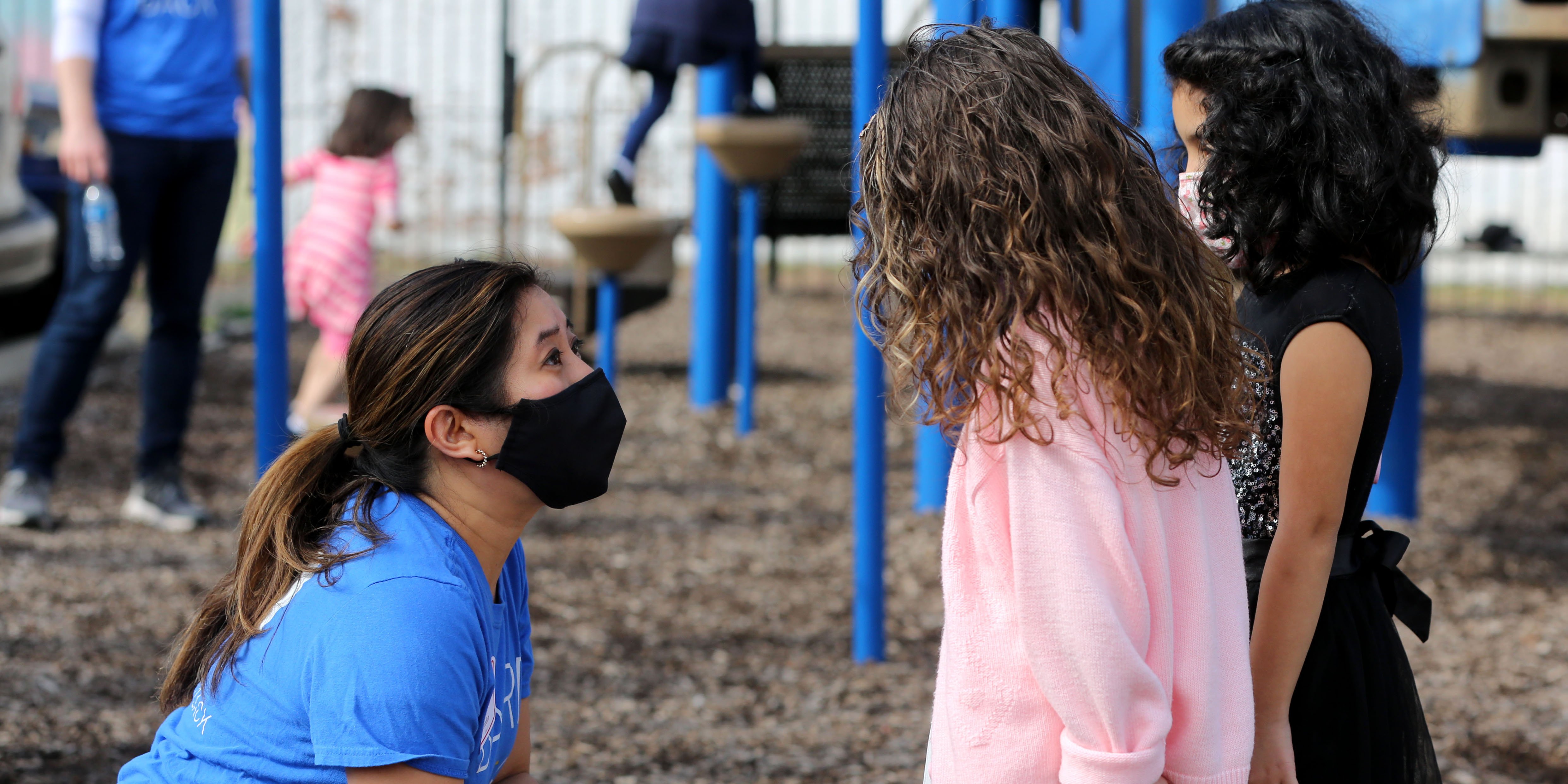 Baird Capital associate talking to children on a playground while volunteering.