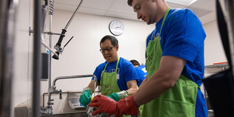 Two Baird Capital Associates doing volunteer work in a kitchen