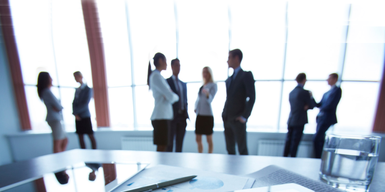 Meeting room filled with professionals talking in groups