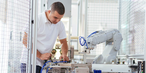 Man working with a robotic industrial piece of equipment in a factory setting