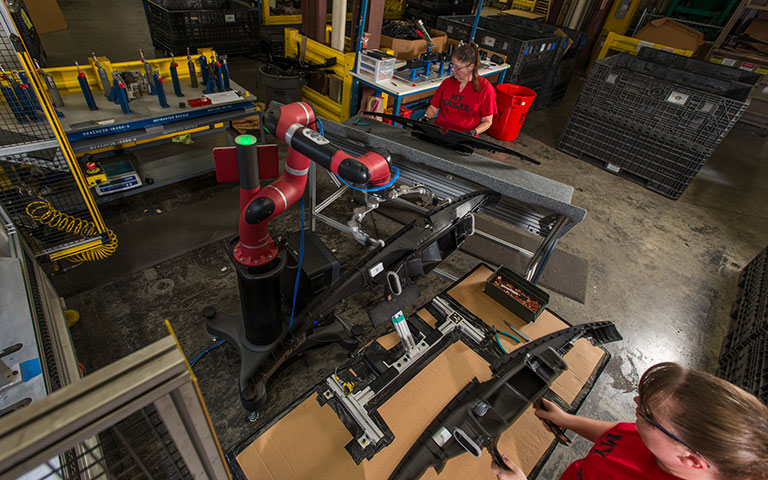 Workers using robotic equipment in a manufacturing setting