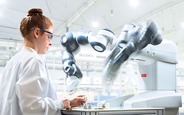 Woman wearing a lab coat and protective glasses using a robotic instrument 