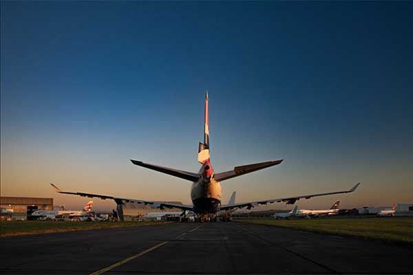 Photo of the back of an airplane sitting on a runway at sunrise