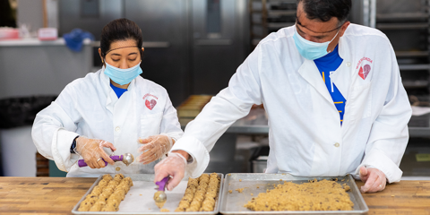 Two Baird Capital Associates scooping cookie dough onto a baking sheet