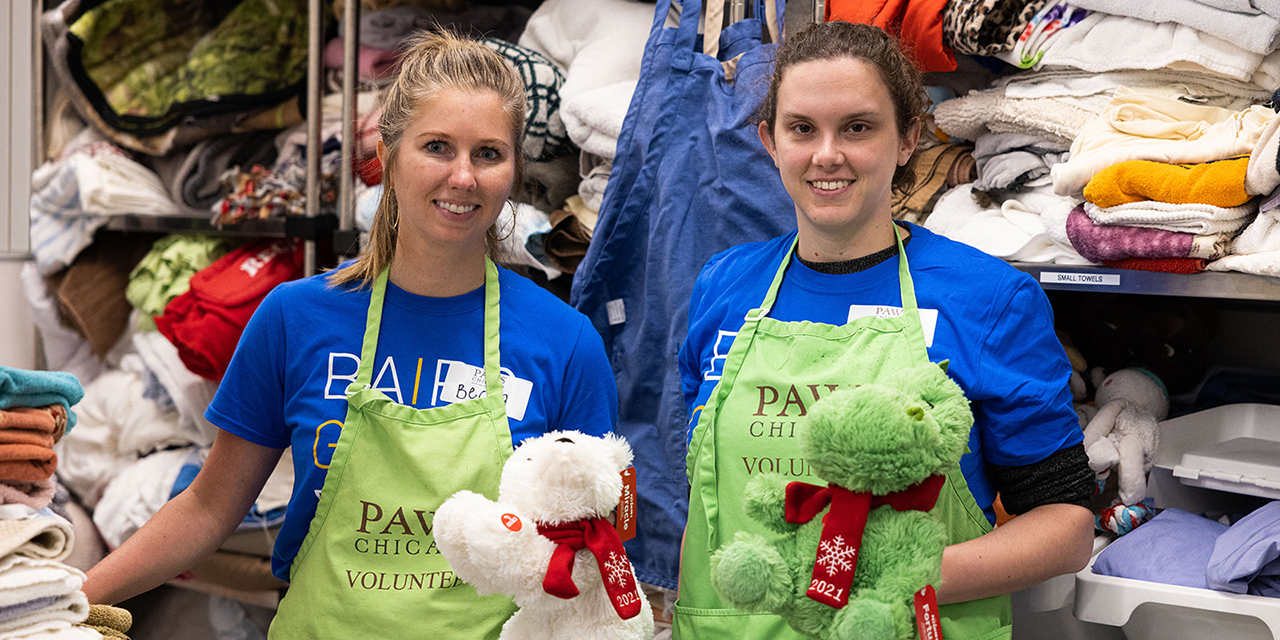 Two Baird Capital Associates holding stuffed animcals while volunteering